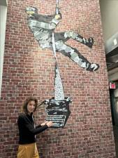 <b>Our contributor, Michele Willens, pretends to type on a mural containing a typewriter.</b> Photo: Courtesy Michele Willens at the Banksky Museum.