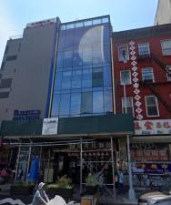 Glass facade building 107 East Broadway, near the corner of Pike Street c. 2022. On the ground floor is Lazhou Ramen. On the third floor, a secret People Republic of China police station. Today, the police station, and the scaffolding are gone. The noodles, happily, remain.