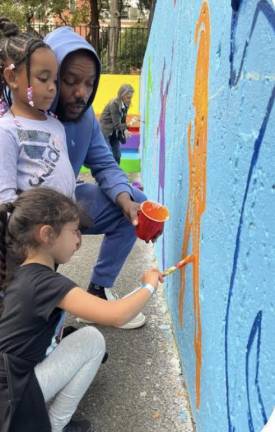 Local residents help repaint outdoor playground space at Harborview Terrace.