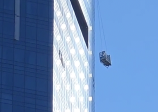 Workers on a dangling scaffold two stories from the top of 25 Columbus Circle, 78 stories above street level.