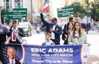 Mayor Eric Adams sidestepped controversy by having his aids carry signs that said he “celebrates Italian-American Heritage. Photo: NYC Mayor’s Office