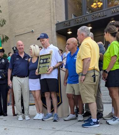 Assistant Chief Charles McElvoy receives an award presented him by Christopher Hoban’s brother, Marty, in blue shirt and shorts.