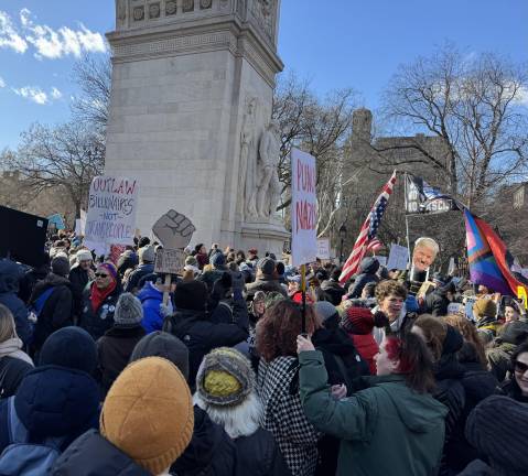 Protestors gather beneath the arch in Washington Square Park, chanting slogans to the sound of horns and drums.