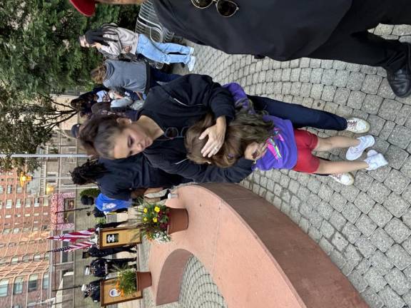 Wendy Feinberg, who lost her dad Carl Feinberg on 9-11, hugs her seven-year-old daughter during a reflective moment before the start of a 9-11 ceremony in a vest pocket memorial park across from the firehouse where her dad worked.