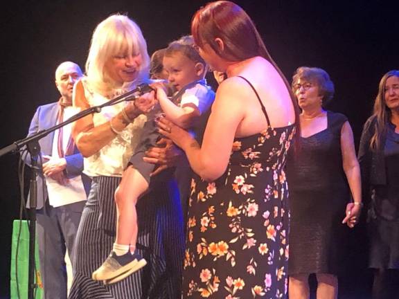 <b>Three generations of McCourts were captured at the mic on May 30 at the memorial for actor, author and raconteur Malachy McCourt. HIs daughter Siobhan McCourt (left of mic) is holding Liam Tiernan McCourt, Malachy’s only great grandchild with Fiona Tiernan, who is Siobhan’s daughter, and granddaughter of Malachy. Behind them is Ellen McCourt, widow of Pulitzer Prize winning Frank McCourt, and to her right, Maggie McCout, the only child of Frank.</b> Photo: Keith J. Kelly