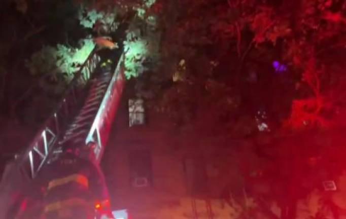 Two firefighters ascend a ladder on W. 88th St. on Oct. 12 in which a 72-year-old man subsequently died on the fourth floor of a five story apartment building.