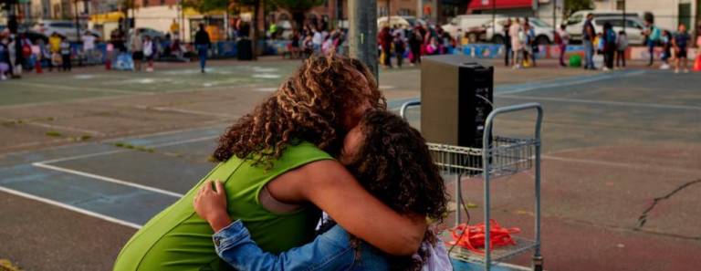 A first grader gets a hug outside of P.S. 503 in Brooklyn on the first day of school, Sept. 8, 2022. In surveys of middle and high school students, girls reported significantly lower levels of satisfaction about classroom experiences and their interactions with peers and adults. (Gabby Jones for Chalkbeat)