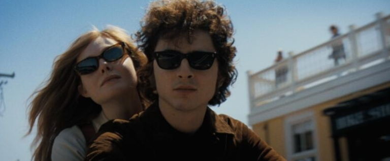 Elle Fanning (left) plays the character Sylvie Russo, based on Bob Dylan’s (Timothée Chalamet’s) one-time girlfriend Suze Rotolo, who was pictured <a rel=nofollow noopener noreferrer href=https://en.wikipedia.org/wiki/The_Freewheelin%27_Bob_Dylan target=_blank>clinging to Dylan’s arm</a> on the cover of the 1963 album <i>“Freewheelin’ Bob Dylan.”</i>