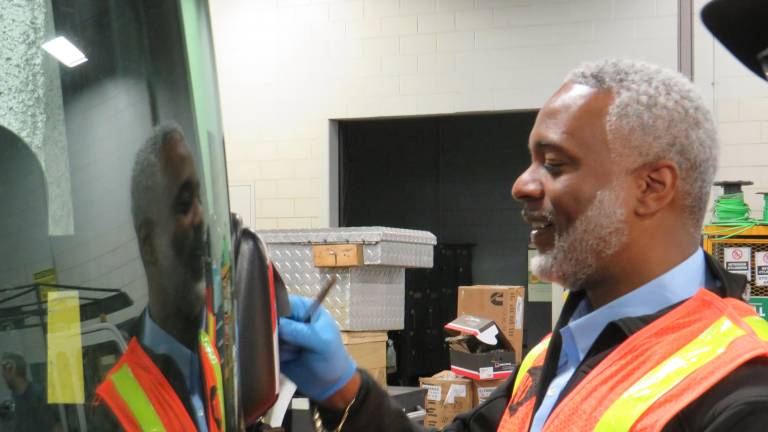 NYC Transit president Demetrius Crichlow, donning an orange safety vest at the Mother Hale Bus Depot, helped out on National Transit Employee Appreciation Day March 18, by changing a bus’s broken mirror, under the guidance of a Hale Bus Depot mechanic.