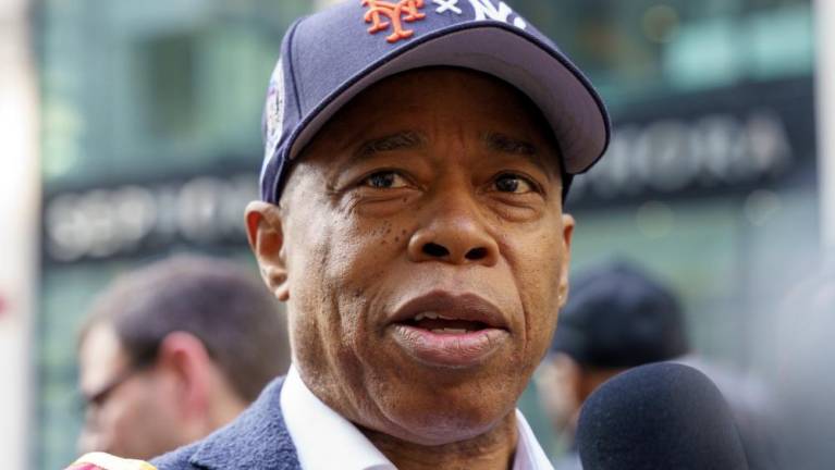 A Mayor for All Post-Seasons: Paying tribute to both of the city’s playoff teams, Eric Adams wore a startling dual-logo Mets / Yankees baseball cap at the Columbus Day Parade, October 14, 2024.